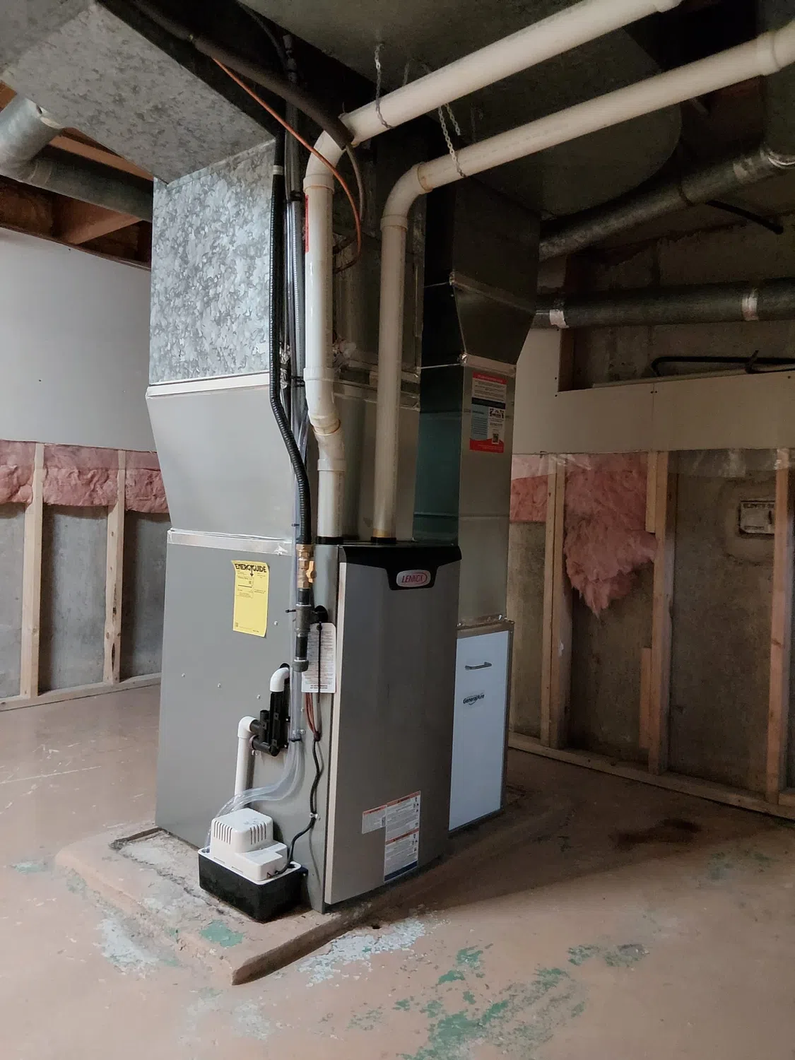 Lennox furnace with supply ductwork, filter cabinet, vent pipes and condensate pump in a basement.